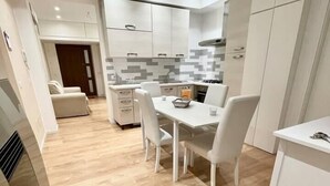 Une cuisine moderne avec des meubles blancs, une table à manger avec des chaises et un plancher en bois.