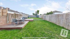 A backyard with a wooden deck, a barbecue grill, and a seating area with chairs. - Stunning 4-Bed House in Gidea Park (Romford)
