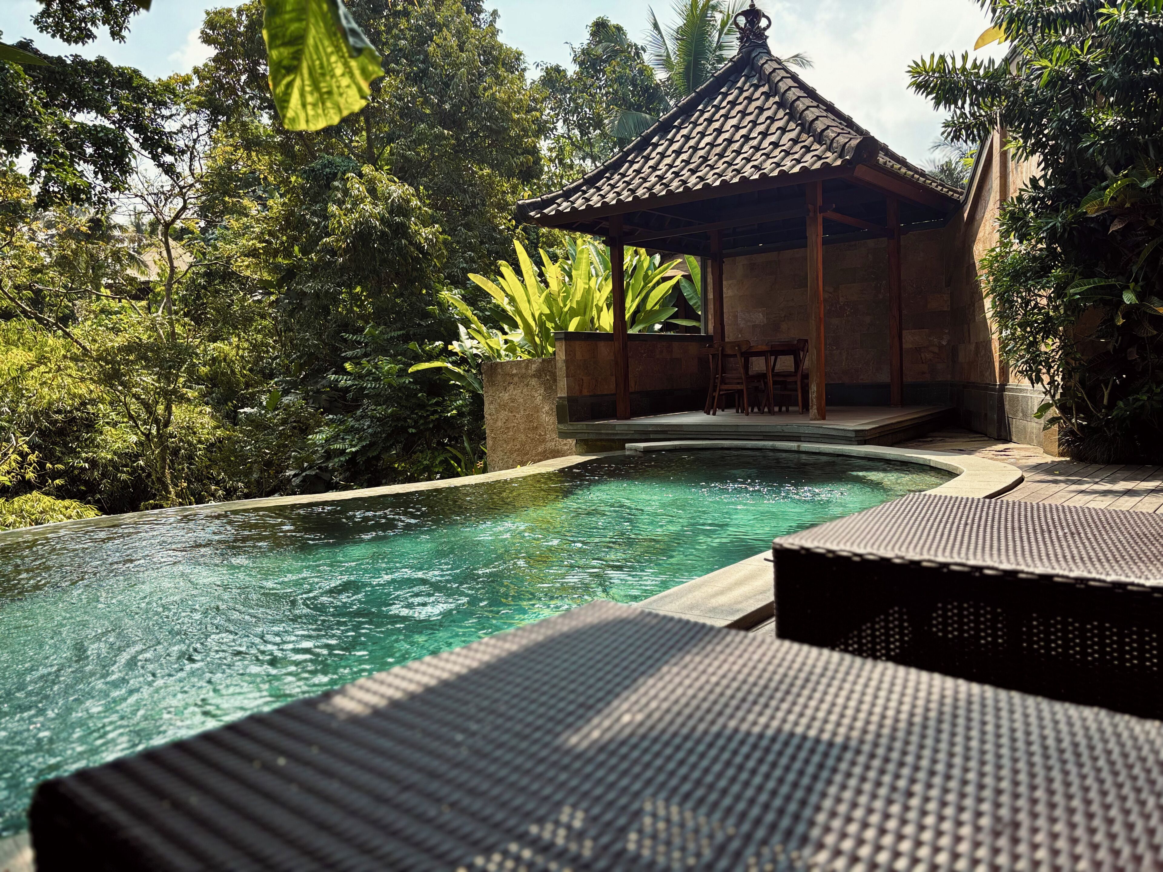 A pool area with a traditional pavilion, surrounded by lush greenery.