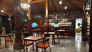 A restaurant with wooden tables and chairs, a bar area, and decorative columns.