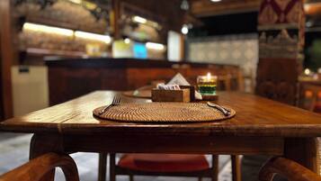 Une table de salle à manger en bois, avec un set de table, une bougie et des couverts.
