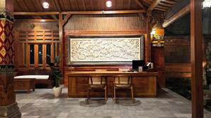 A traditional interior with a wooden ceiling, a large carved panel, and a seating area with chairs and a table.