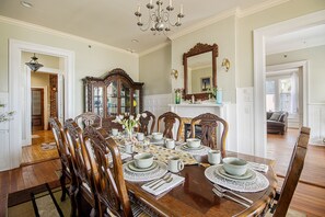 A dining room with a wooden table set for six, surrounded by ornate chairs. A large mirror and a fireplace are visible in the background. - Beautiful Beach House sleeps 12 (Biloxi)
