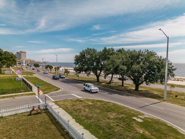 A coastal road with a white fence, trees, and a stop sign. - Beautiful Beach House sleeps 12 (Biloxi)