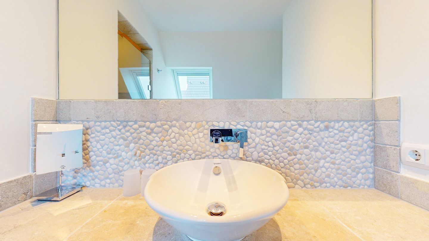 Un bagno con un lavandino bianco, un erogatore di asciugamani e uno specchio.