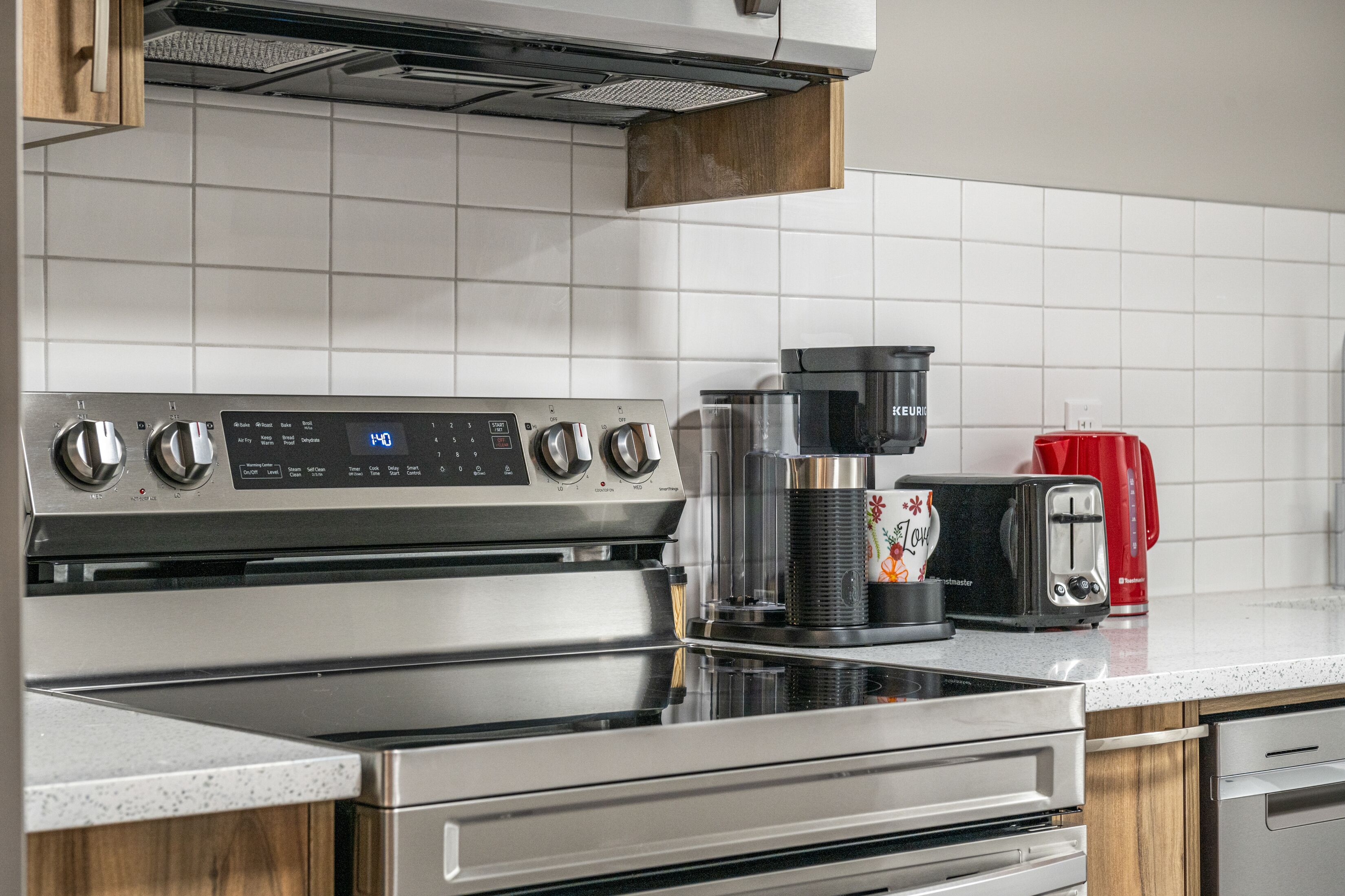 A modern kitchen with stainless steel appliances, including a stove and a coffee maker.