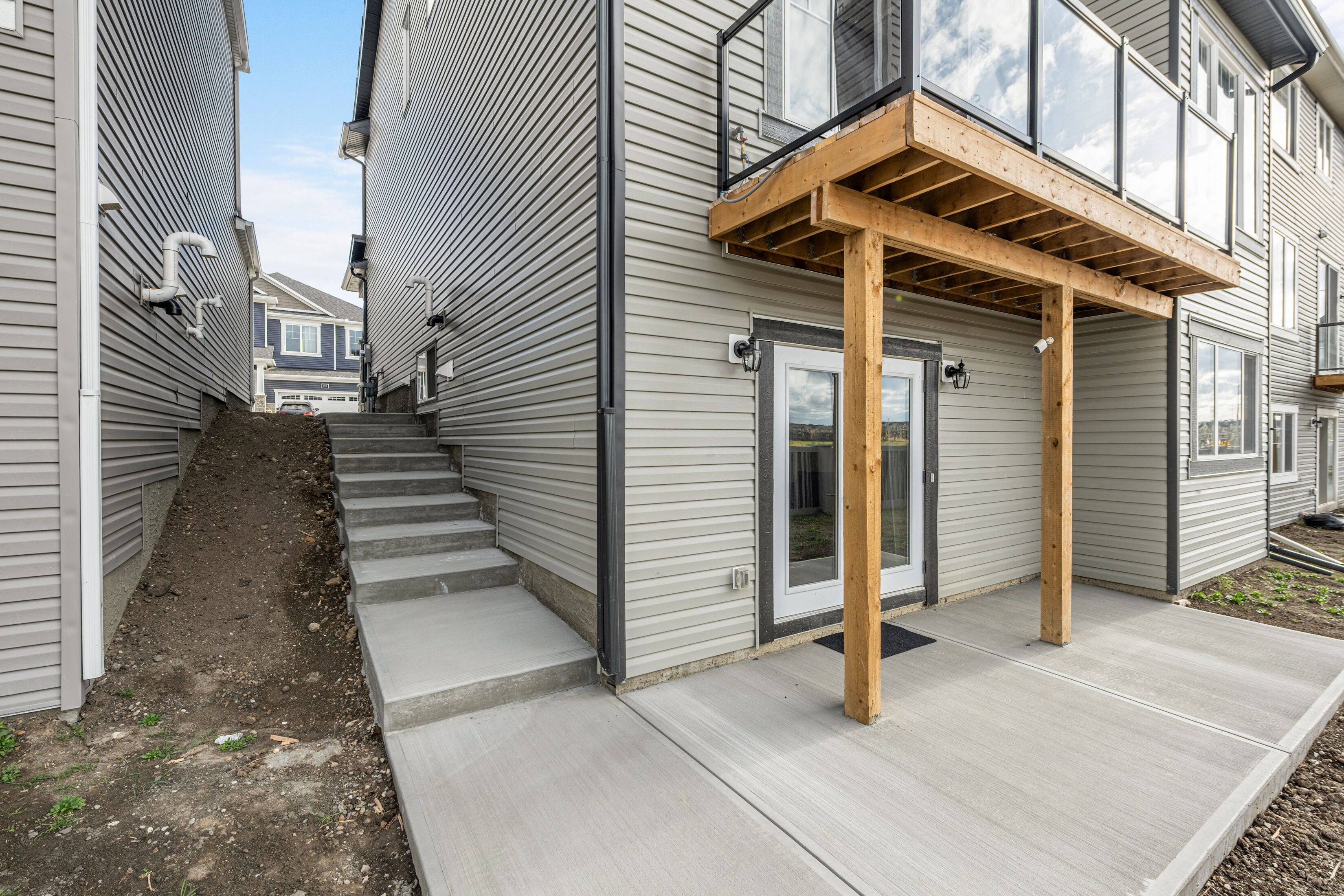 A residential building with a wooden deck, a front door, and a staircase leading to the entrance.