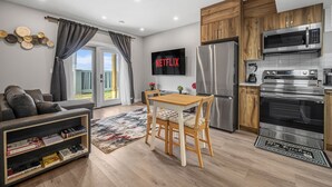 A modern kitchen with a built-in microwave, oven, and refrigerator. There is a dining table with chairs and a flat-screen TV mounted on the wall. - Sunny Walk-out Unit | Free HiSpeed WiFi & Parking | Near Grocery (Calgary)