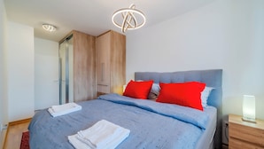 Une chambre moderne avec un grand lit, une armoire en bois et une table de chevet avec une lampe.
