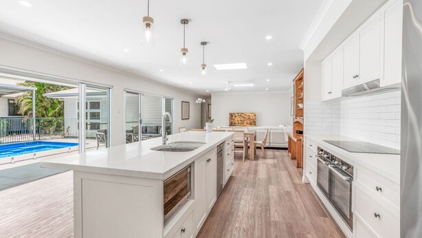 A modern kitchen with a central island, a dining area, and a view of a swimming pool. - 11 Esprit Drive - Rainbow Shores. Gorgeous beach house. Walk to beach (Rainbow Beach)