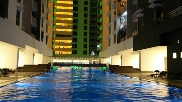 A swimming pool with steps leading up to it, surrounded by buildings with balconies. - Apartment with Balcony - The Aliff Residences
 (Johor Bahru)