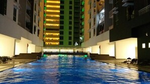 Une piscine avec des marches menant à l’eau, entourée d’immeubles dotés de balcons.