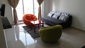 A modern living room with a sofa, a red table, and two bean bag chairs. - Apartment with Balcony - The Aliff Residences
 (Johor Bahru)