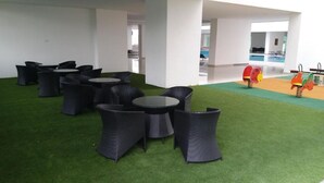 A lounge area with black wicker furniture and artificial green turf. - Apartment with Balcony - The Aliff Residences
 (Johor Bahru)