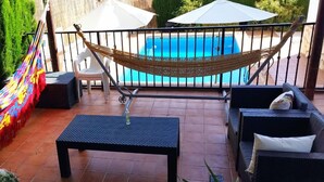 Une terrasse avec un hamac, une piscine et du mobilier d’extérieur.