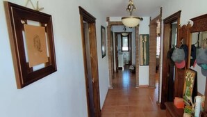 Un couloir avec un cadre de porte en bois, un tableau encadré accroché au mur et un ventilateur de plafond.
