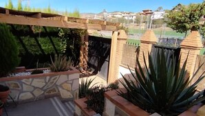 Un espace patio agrémenté d’un mur en pierre, d’une pergola en bois et de différents pots de plantes.