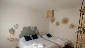 Ein Schlafzimmer mit zwei Betten, Holzboden und einer Pendelleuchte.