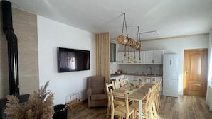Eine moderne Küche mit weißen Schränken, einem Essbereich mit Holzkästen und einem an der Wand befestigten Fernseher.