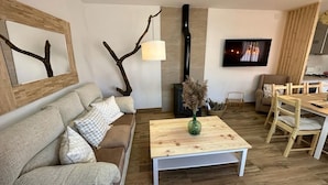Ein Wohnzimmer mit Sofa, Couchtisch und einem an der Wand befestigten Fernseher.