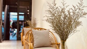 A corridor with wicker furniture and a vase of dried flowers. - Lanha Hotel-Homestay (Hanoi)