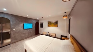 A modern hotel room with a large bed, a flat-screen TV mounted on the wall, a small seating area, and a painting on the wall. - Lanha Hotel-Homestay (Hanoi)