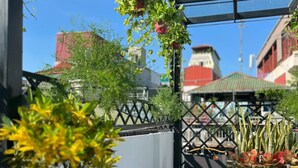 An outdoor patio area with a glass roof, potted plants, and outdoor seating. - Lanha Hotel-Homestay (Hanoi)