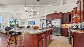 A modern kitchen with a large island, stainless steel appliances, and wooden cabinets. - The Tulum House (San Diego)