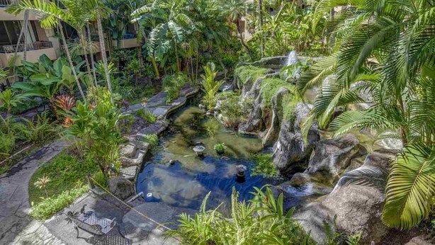 A lush indoor garden with a small waterfall and a seating area.