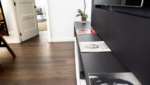 A room with a wooden floor, a black sofa, and a small table with magazines.