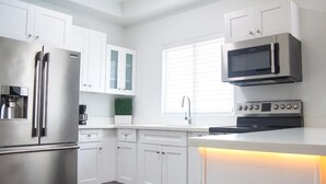 A modern kitchen with white cabinetry, stainless steel appliances, and a built-in oven.