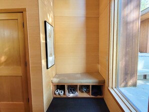 Une pièce d’angle avec un banc en bois, un porte-chaussures et un tableau encadré au mur.
