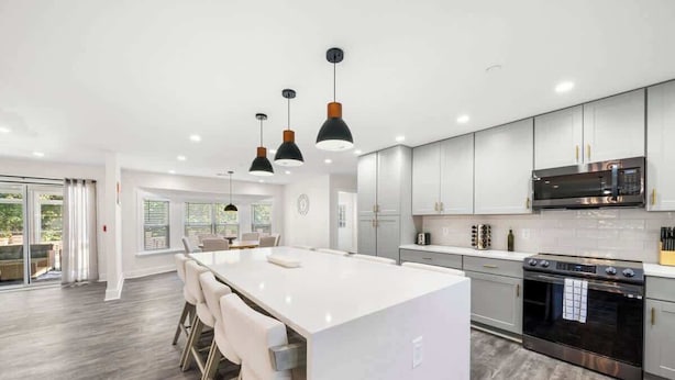 A modern kitchen with a central island, stainless steel appliances, and pendant lighting. - Grand Retreat: Luxury Vacation for Large Groups (Fayetteville)