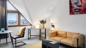 A modern loft-style room with a sloped ceiling, a sofa, a table, a lamp, a plant, and a painting. - Studio Apartment 'Vogelsberger Bett Die 2' with Wi-Fi (Alsfeld)