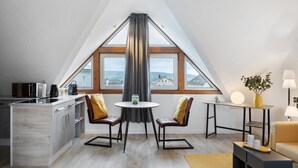 A modern kitchen with a dining area, a small table, and a view through a large window. - Studio Apartment 'Vogelsberger Bett Die 2' with Wi-Fi (Alsfeld)