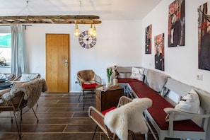 A modern living room with a sofa, chairs, a wooden door, and wall art.