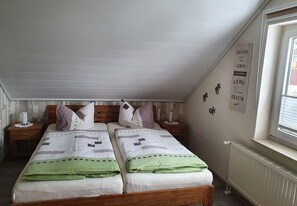 A bedroom with two beds, a window, and a radiator.