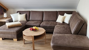 Un canapé modulable, une table basse ronde, une petite table d’appoint et une lampe.