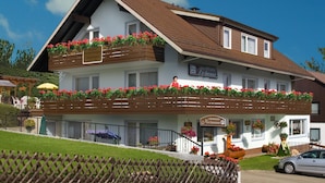 Un bâtiment à deux étages doté d’un balcon, d’une enseigne indiquant qu’il s’agit d’un restaurant, et d’une voiture garée devant.