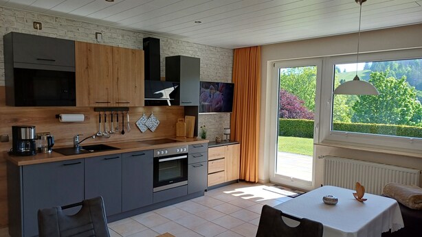 A modern kitchen with grey cabinets, a wooden countertop, and a built-in oven. - Apartment No. 2: Brand-New Flat in Altenau – Near Spa, Prime Location with Sauna, Wi-Fi & EV Charging (Altenau)
