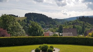 A well-maintained garden with a circular hedge, a small tree, and a red flower bed. - Apartment No. 2: Brand-New Flat in Altenau – Near Spa, Prime Location with Sauna, Wi-Fi & EV Charging (Altenau)