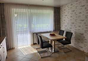 Un espace repas comprenant une table, des chaises et une vue dégagée grâce à de grandes fenêtres.