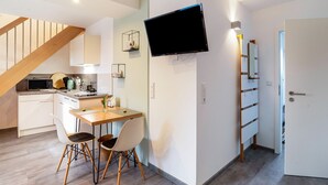 A modern kitchen with a dining area, a TV mounted on the wall, and a staircase. - Apartment 'Kräuterglück' with Shared Garden and Wi-Fi (Ötisheim)