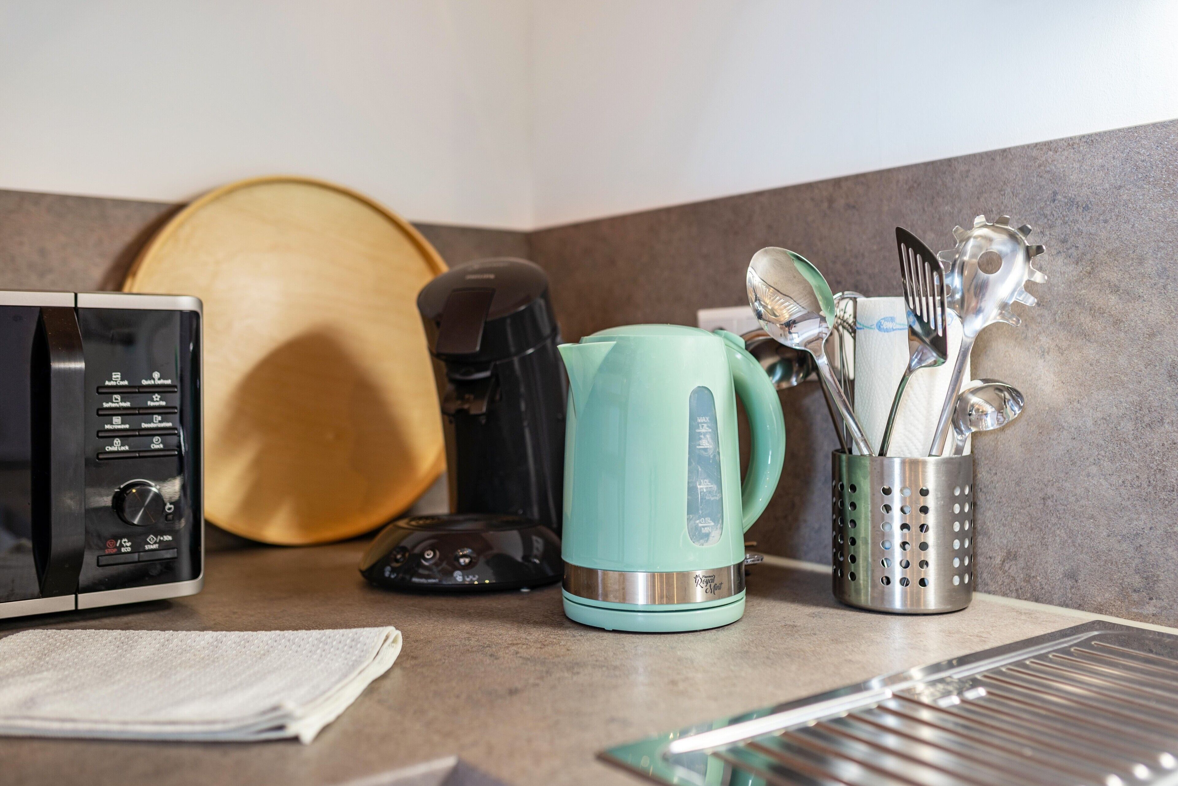 Un plan de travail de cuisine avec une machine à café, une bouilloire et des ustensiles.
