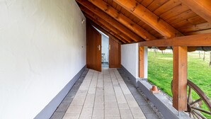 A covered corridor with wooden beams, a tiled floor, and a view of a grassy area. - Apartment 'Kräuterglück' with Shared Garden and Wi-Fi (Ötisheim)