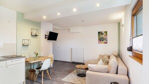 A modern living space with a kitchen, dining area, and a sofa. - Apartment 'Kräuterglück' with Shared Garden and Wi-Fi (Ötisheim)