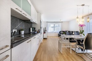 Een moderne keuken met marmeren aanrecht, een eethoek met een tafel en stoelen, en een zithoek met een bank en salontafel.