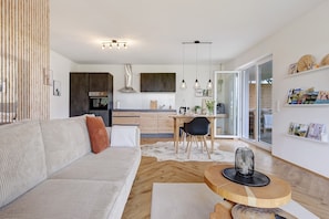 Una sala de estar moderna con un sofá, una mesa de comedor y una cocina al fondo.