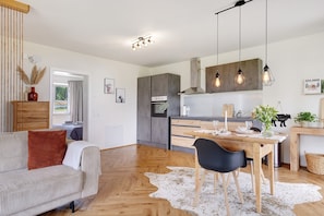 Una cocina moderna con armarios de madera, una mesa de comedor y lámparas colgantes.
