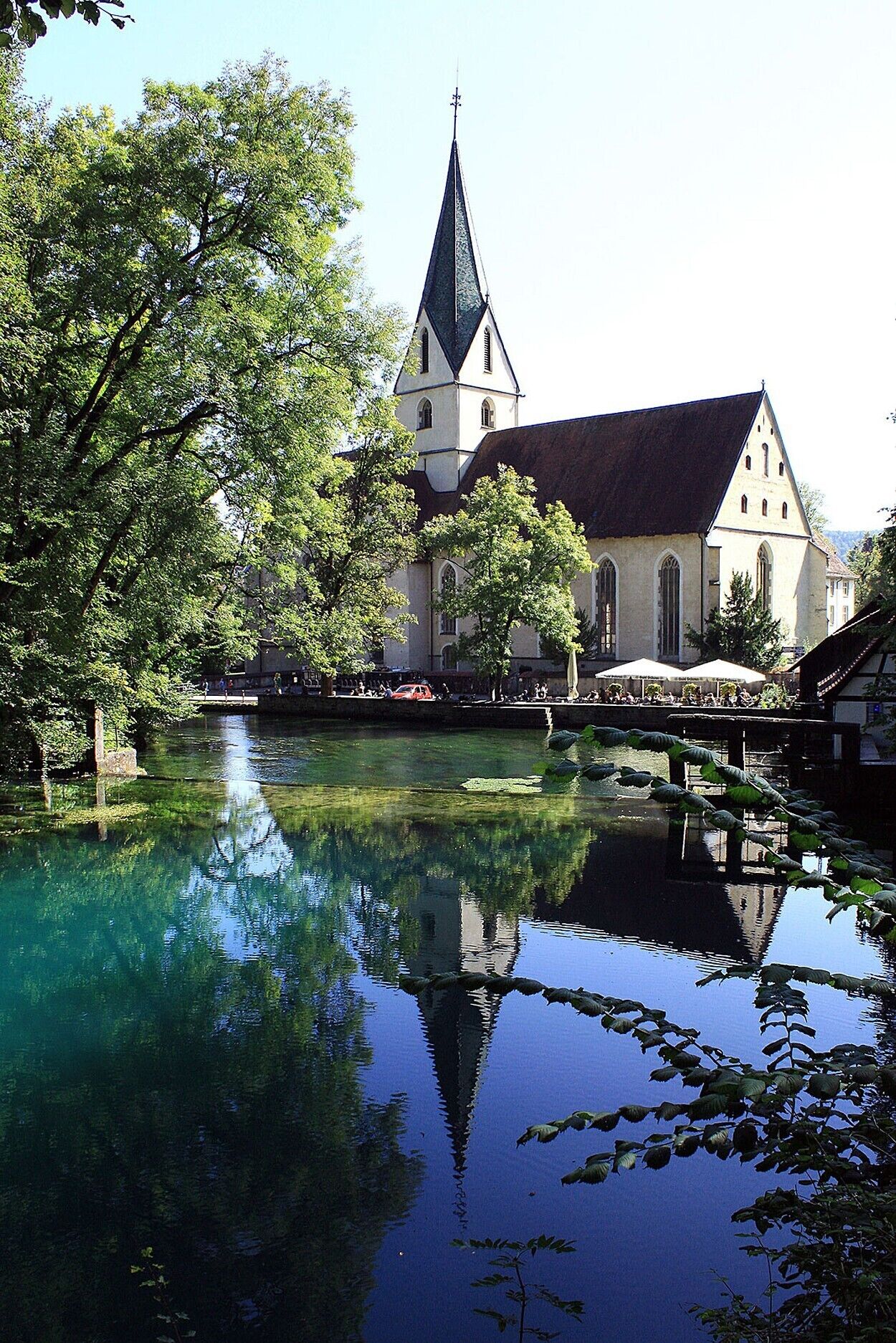 A church with a prominent tower and a calm water body in front.